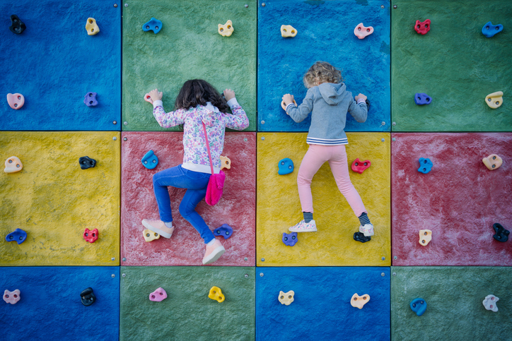 Two girls hanging on holds on climbing wall