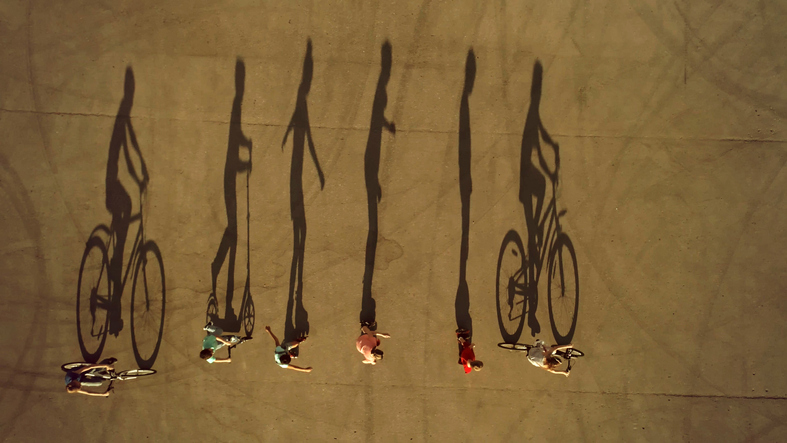 Kids on Wheels Cast Long Shadows. Cycling, Roller Skating and Scootering